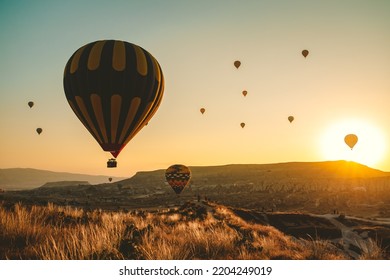 Silhouette Of Many Colorful Hot Air Balloons In Sunrise Bright Sky. Orange Sun Rise Up Over Cappadocia Goreme Valley Landscape. Amazing Natural Summer Morning Scenery. Best Famous Travel Location