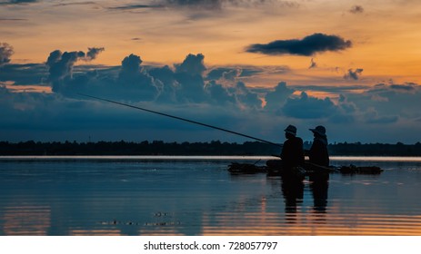 Silhouette Mature Couple Fishing Over Lake In Sunset 