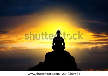 Silhouette of the meditating person against an approaching the dark clouds at sunset