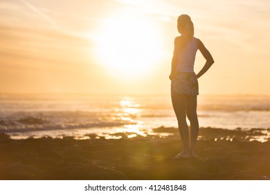 Silhouette of meditative, sensual blonde woman watching sunset at the beach.