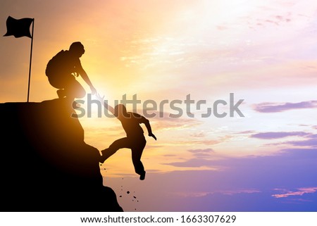 Silhouette of men helping pull people up from high cliffs.teamwork and backing or aid to support team to achievement or successful in business.