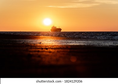 The Silhouette Of The Merchant Ship On The Horizon, Going Into The Sunset.