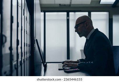 Silhouette of a middle-aged engineer working in a server room.
