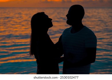 silhouette of a middle-aged man and woman couple against the backdrop of a sunset in the Maldives - Powered by Shutterstock