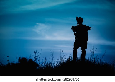 Silhouette Of Military Soldier Or Officer With Weapons At Night. Shot, Holding Gun, Blue Colorful Sky, Background