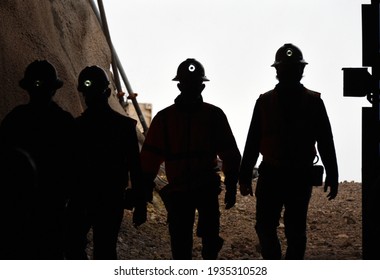 Silhouette of miners with headlamps entering a mine - Shutterstock ID 1935310528