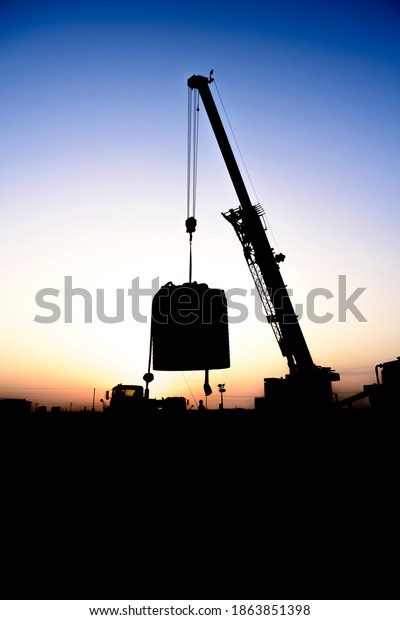 Silhouette of Mobile crane working in the oilfield at\
sunset 