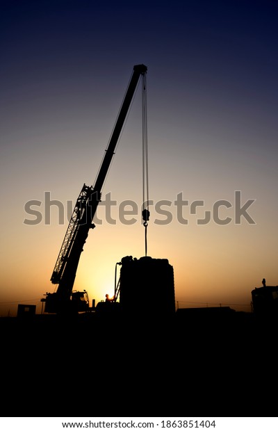 Silhouette of Mobile crane working in the oilfield at\
sunset 