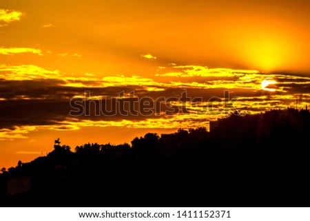 Silhouette of monument to Salawat Yulaev, folk hero on a horse against a bright yellow sky with clouds and orange sun disk at city sunset. Salavat Yulayev, Ufa, Bashkortostan, Russia.