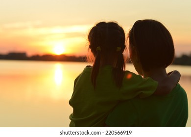 Silhouette Of Mother And Daughter On Sunset Background