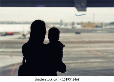 Silhouette of mother holding on hands little toddler boy with window of airport on background. Departure and arrival. Single mother with child emigration. Mom with son meeting or seeing off father - Shutterstock ID 1519342469
