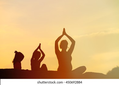 Silhouette Of Mother And Kids Doing Yoga At Sunset