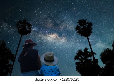 Silhouette Mother And Son Asian Couple Standing Under The Shadow Of A Big Tree. Looking At The Stars And The Milky Way On The Romantic And Happy Night. Long Exposure, With Grain.