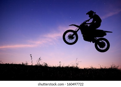  Silhouette Of A Motorcycle Racer Commits High Jump On Beautiful Sunset Sky Background 