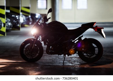 Silhouette of motorcycle standing underground parking with running engine - Powered by Shutterstock