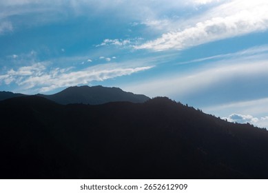 Silhouette of mountain range against dramatic sky. Minimalist landscape, nature's power, serene beauty, endless horizons