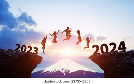 Silhouette of multinational people jumping from 2023 to 2024. 2024 New Year concept. New year's card 2024. Wide angle visual for banners or advertisements.