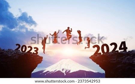 Silhouette of multinational people jumping from 2023 to 2024. 2024 New Year concept. New year's card 2024. Wide angle visual for banners or advertisements.
