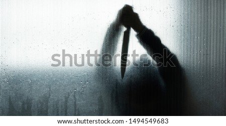 Silhouette of murderer or robber with big knife in hand behind frosted glass in  bathroom background,concept of scary crime scene of horror or thriller movies,Halloween theme