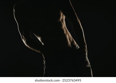 Silhouette of a muscular man in low light, emphasizing his abs and physique. Capturing strength, fitness, and the male body in an artistic and dramatic manner. - Powered by Shutterstock