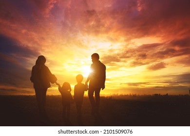 Silhouette Of Muslim Family Holding Hands Together While Walking Toward City At Sunrise Time