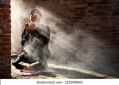 Silhouette of muslim man having worship and praying for fasting and Eid of Islam culture in old mosque with lighting and smoke background