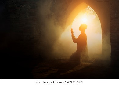 Silhouette of muslim man having worship and praying for fasting and Eid of Islam culture in old mosque with lighting and smoke background                                   - Shutterstock ID 1703747581