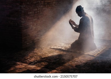 Silhouette Of Muslim Man Having Worship And Praying For Fasting And Eid Of Islam Culture In Old Mosque With Lighting And Smoke Background              