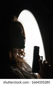 Silhouette Noir Style Portrait Of Young Brunette Female Model Holding Gun Barrel Up.