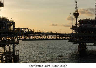 Silhouette Of An Oil Production Platform Connected With A Bridge At Oil Field During Sunset