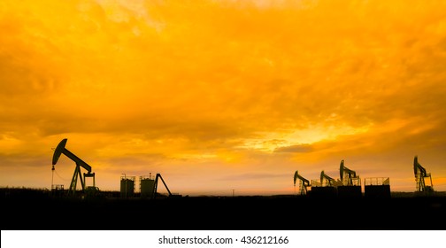 Silhouette of Oil pumps at oil field with nice sunset sky background