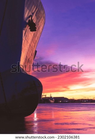 Silhouette oil Tanker Ship moored at harbor against colorful Sunset Clouds sky background in evening time and vertical frame