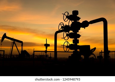 Silhouette of oil well manifold in the oilfield at sunset
