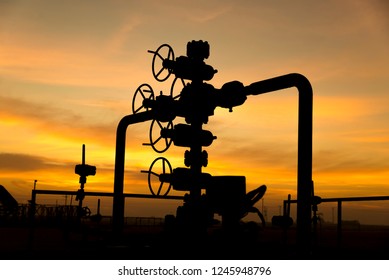 Silhouette of oil well manifold in the oilfield at sunset