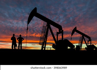 Silhouette Of Oil Workers At An Oil Field Pumpjack Site Against A Dramatic Sky.