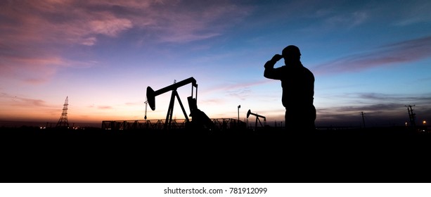 Silhouette of oilfield worker at  crude oil pump in the oilfield at sunset.