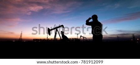 Silhouette of oilfield worker at  crude oil pump in the oilfield at sunset.