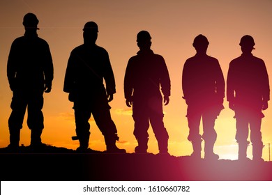 Silhouette Of Oilfield Workers At Sunset In Oilfield
