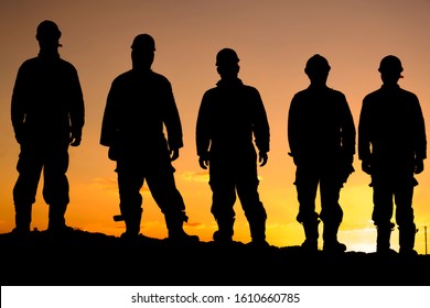 Silhouette of oilfield workers at sunset in oilfield
