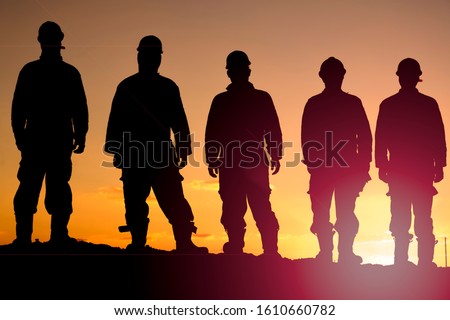 Silhouette of oilfield workers at sunset in oilfield
