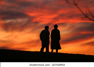 Silhouette Of An Old Couple Walking At Sunset