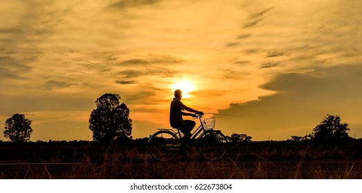 silhouette of old man on bicycle go home