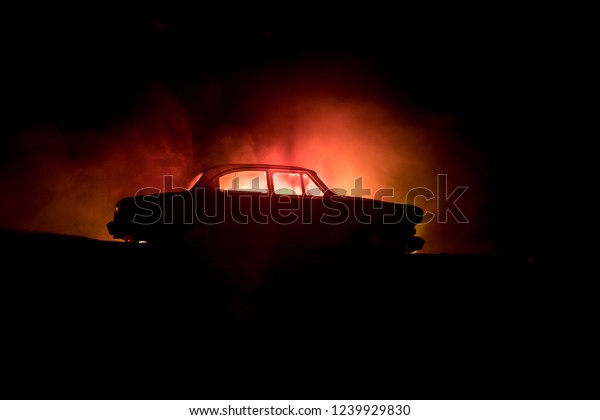 Silhouette of old\
vintage car in dark foggy toned background with glowing lights in\
low light. Selective\
focus