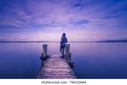 Silhouette on the pier. Lake and clouds are long exposure. Bright toning. - Powered by Shutterstock