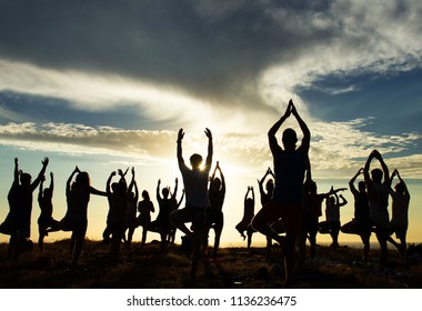 Silhouette of an outdoor yoga class at sunset