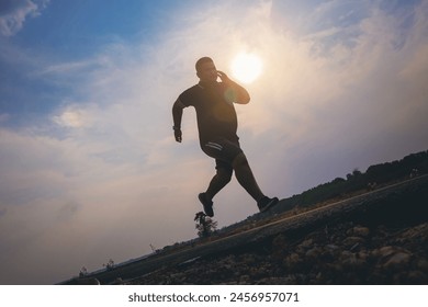 Silhouette of overweight man running sprinting on road. Fat man runner jogging at outdoor workout. Exercise concept for weight control. - Powered by Shutterstock