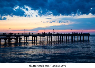silhouette of palanga pier with people in baltic sea during beautiful sunset with clouds