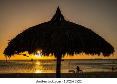 A Silhouette Of A Palapa At Sunset On Palm Beach In Aruba