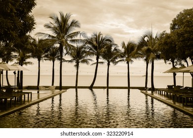 Silhouette palm tree on the beach with swimming pool in hotel resort - vintage filter effect - Shutterstock ID 323220914