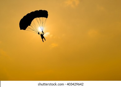 Silhouette of parachute on sunset background.